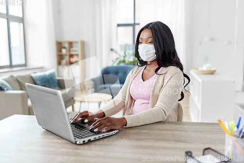 Image of woman in mask with laptop working at home office