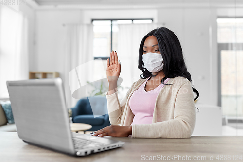Image of woman in mask with laptop having video call