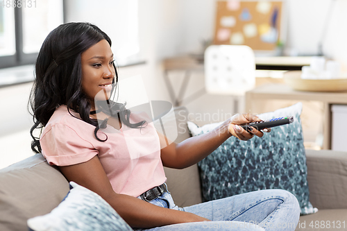 Image of happy african american woman watching tv at home