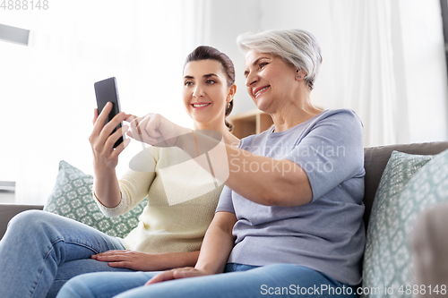 Image of daughter and senior mother with smartphone at home