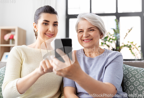 Image of daughter and senior mother with smartphone at home