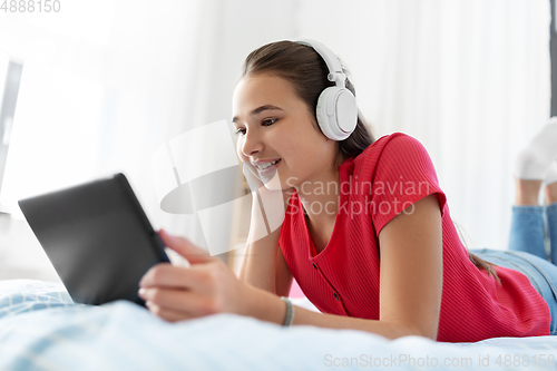 Image of girl in headphones listening to music on tablet pc