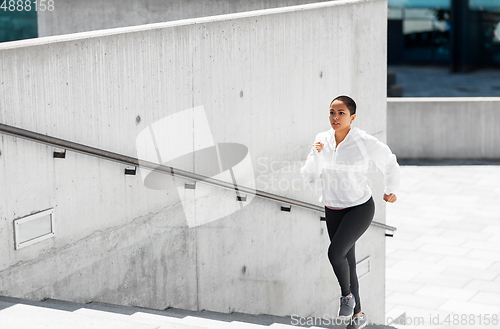 Image of african american woman running upstairs outdoors