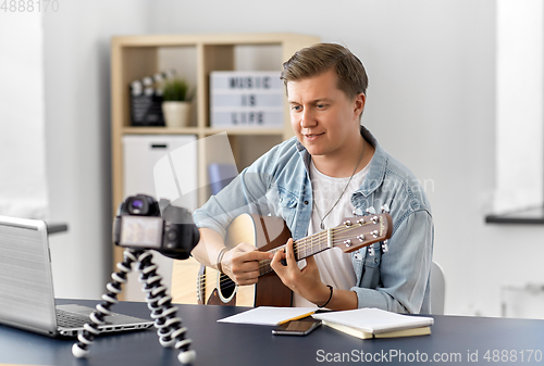 Image of man or blogger with camera playing guitar at home