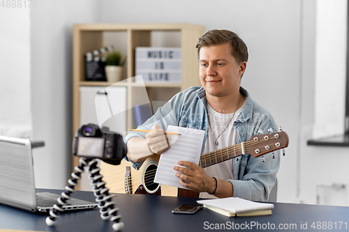 Image of man or blogger with camera, music book and guitar