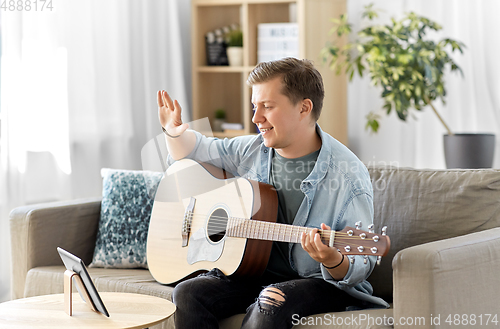 Image of man with tablet pc and guitar having video call