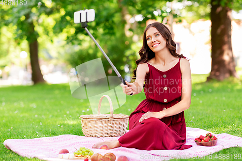 Image of happy woman with smartphone taking selfie at park