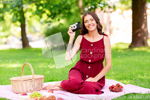 Image of happy woman with camera on picnic at park