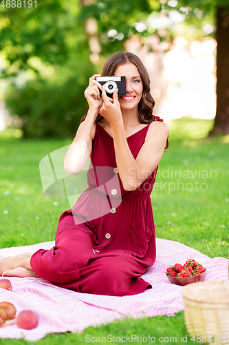 Image of happy woman with camera on picnic at park