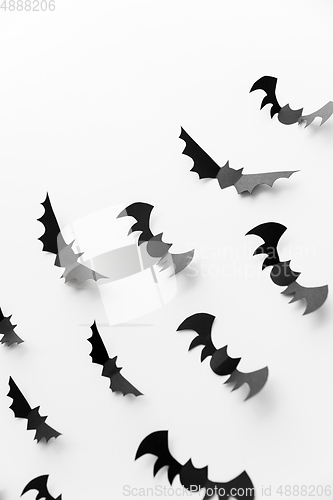 Image of flock of black paper bats over white background