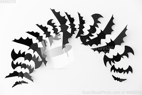 Image of flock of black paper bats over white background