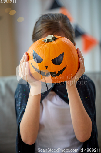 Image of girl in halloween costume with pumpkin at home