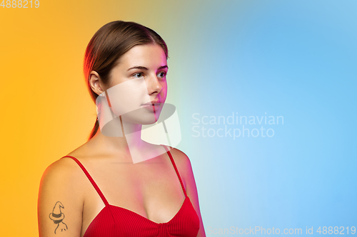 Image of Caucasian young woman\'s portrait on gradient studio background in neon