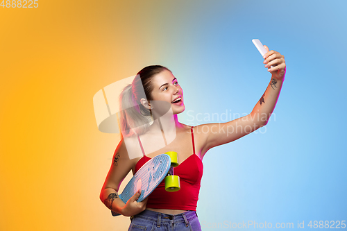 Image of Caucasian young woman\'s portrait on gradient studio background in neon