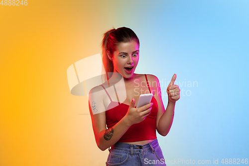 Image of Caucasian young woman\'s portrait on gradient studio background in neon