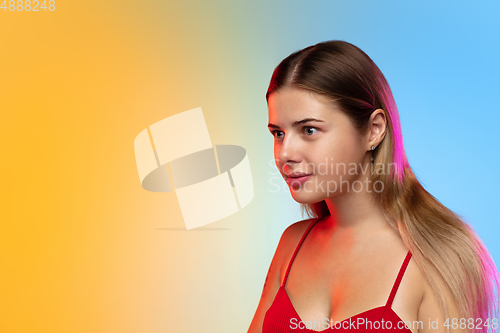 Image of Caucasian young woman\'s portrait on gradient studio background in neon