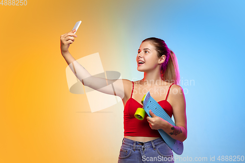 Image of Caucasian young woman\'s portrait on gradient studio background in neon