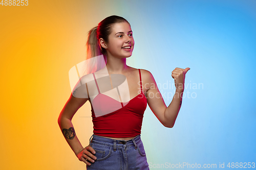 Image of Caucasian young woman\'s portrait on gradient studio background in neon