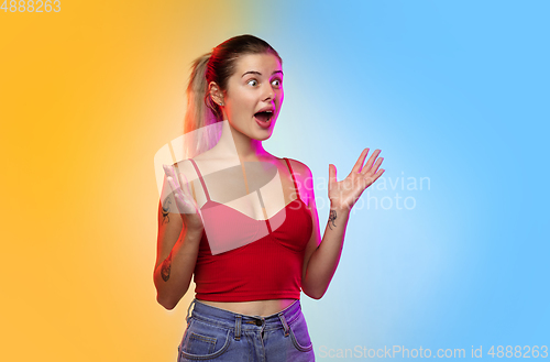 Image of Caucasian young woman\'s portrait on gradient studio background in neon