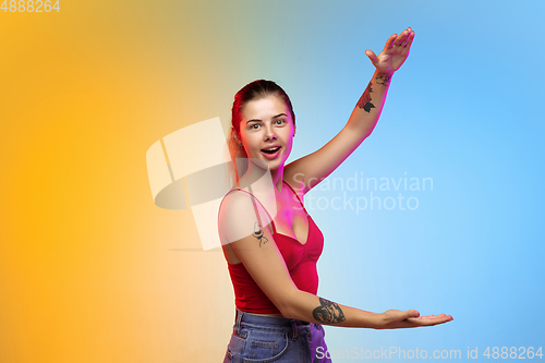 Image of Caucasian young woman\'s portrait on gradient studio background in neon
