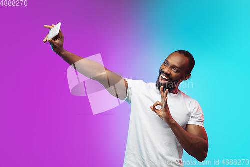 Image of African-american young man\'s portrait on gradient studio background in neon