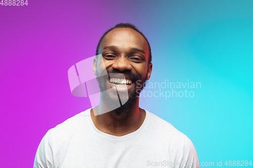 Image of African-american young man\'s portrait on gradient studio background in neon, close up