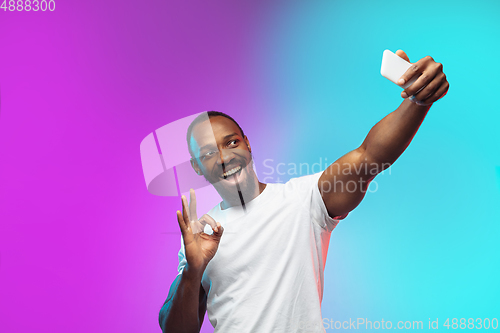 Image of African-american young man\'s portrait on gradient studio background in neon