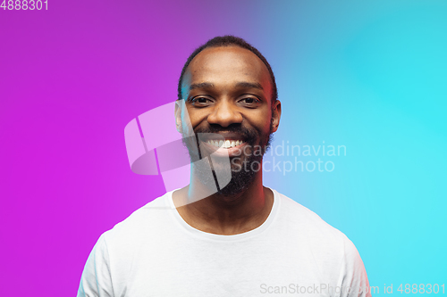 Image of African-american young man\'s portrait on gradient studio background in neon, close up