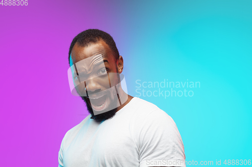 Image of African-american young man\'s portrait on gradient studio background in neon, close up