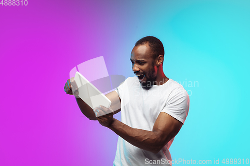 Image of African-american young man\'s portrait on gradient studio background in neon