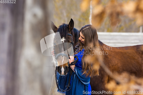 Image of Touching portrait of a girl in a blue dress with a horse