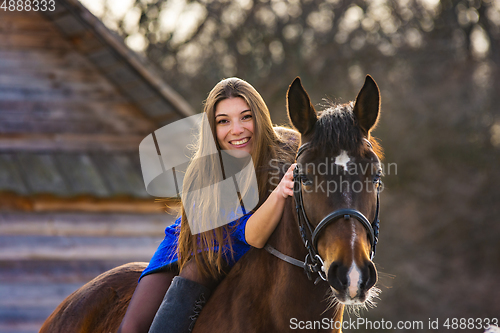 Image of Girl in a blue dress on a beautiful horse
