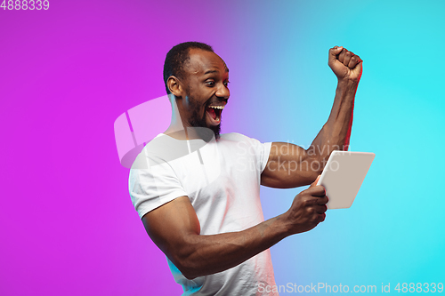 Image of African-american young man\'s portrait on gradient studio background in neon