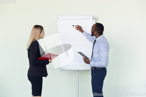 Image of Young businessman working with colleague using flipchart, copyspace