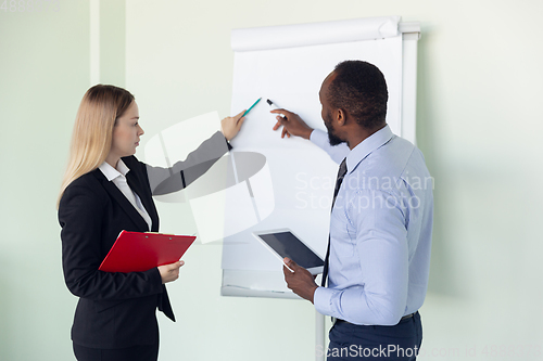 Image of Young businessman working with colleague using flipchart, copyspace