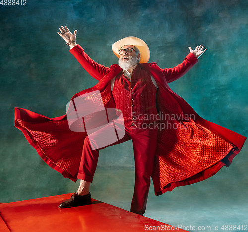 Image of Modern stylish Santa Claus in red fashionable suit and cowboy\'s hat on dark background