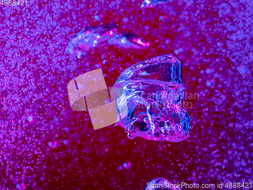 Image of Close up view of the cold and fresh cola with bright bubbles in neon light