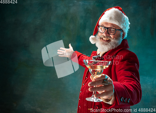 Image of Modern stylish Santa Claus in red fashionable suit and cowboy\'s hat on dark background