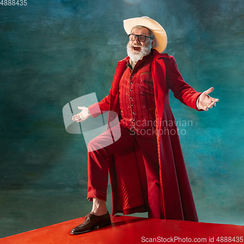 Image of Modern stylish Santa Claus in red fashionable suit and cowboy\'s hat on dark background