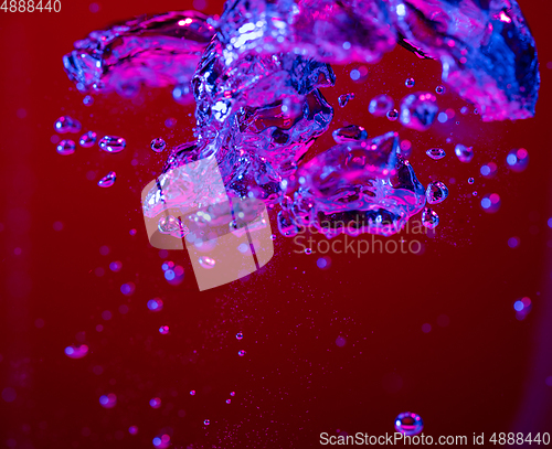 Image of Close up view of the cold and fresh cola with bright bubbles in neon light