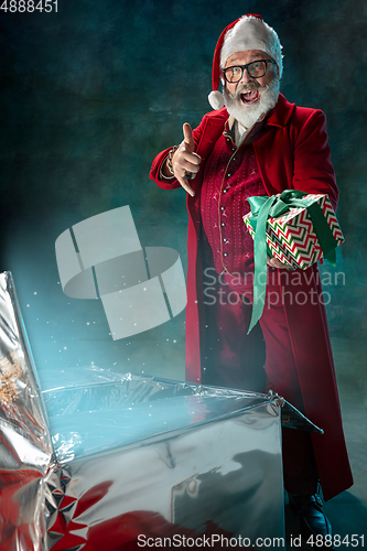 Image of Modern stylish Santa Claus in red fashionable suit and cowboy\'s hat on dark background