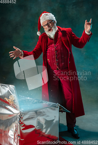 Image of Modern stylish Santa Claus in red fashionable suit and cowboy\'s hat on dark background