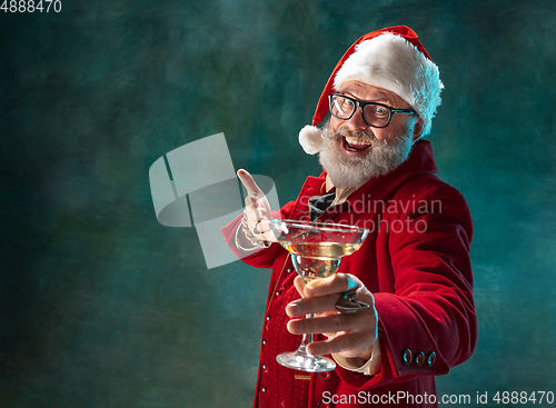 Image of Modern stylish Santa Claus in red fashionable suit and cowboy\'s hat on dark background