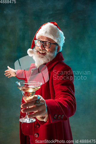 Image of Modern stylish Santa Claus in red fashionable suit and cowboy\'s hat on dark background