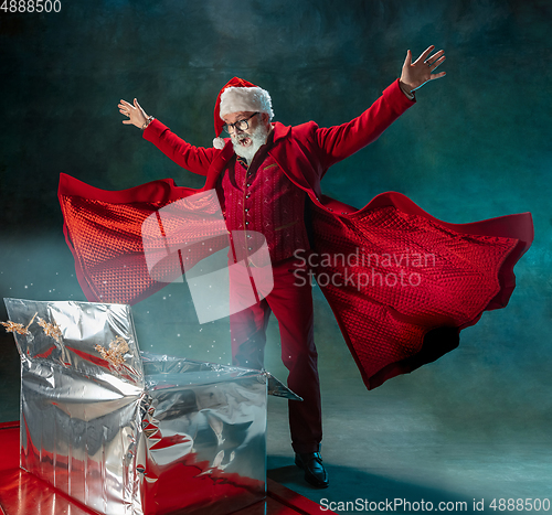 Image of Modern stylish Santa Claus in red fashionable suit and cowboy\'s hat on dark background