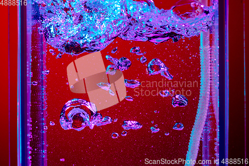 Image of Close up view of the cold and fresh cola with bright bubbles in neon light