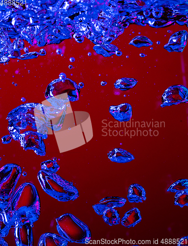 Image of Close up view of the cold and fresh cola with bright bubbles in neon light