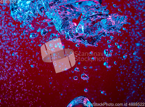 Image of Close up view of the cold and fresh cola with bright bubbles in neon light