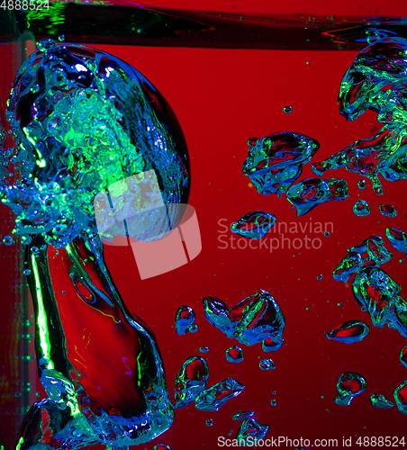 Image of Close up view of the cold and fresh cola with bright bubbles in neon light