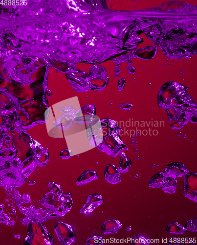 Image of Close up view of the cold and fresh cola with bright bubbles in neon light